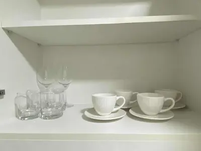 a white shelf with cups and glasses on it at Bright Unit with Balcony near Okada & Airport-6C in Manila