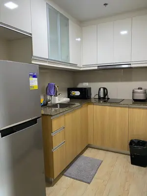 a kitchen with wooden cabinets and a refrigerator at Bright Unit with Balcony near Okada & Airport-6C in Manila