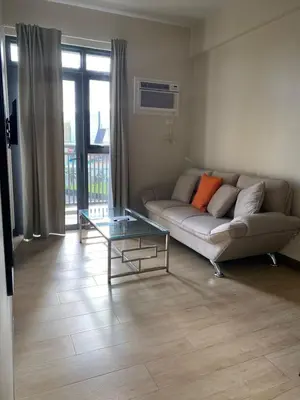 a living room with a couch and a glass table at Bright Unit with Balcony near Okada & Airport-6C in Manila
