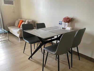 a dining room table with chairs and a couch at Bright Unit with Balcony near Okada & Airport-6C in Manila