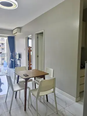a dining room with a wooden table and white chairs at WP1102 Facing pool view near MOA in Manila