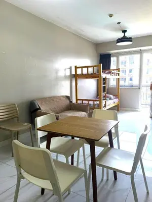 a living room with a table and chairs and a couch at WP1102 Facing pool view near MOA in Manila