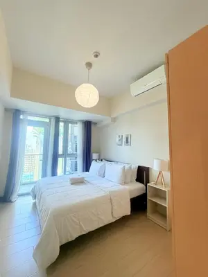 a bedroom with a large white bed and a window at Spacious 2 Bedroom with StunningView in Uptown BGC in Manila