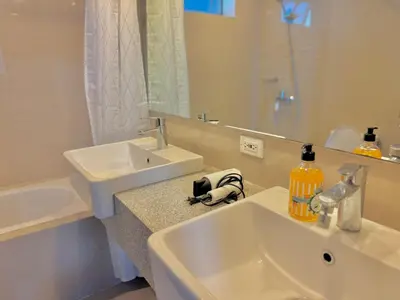 a white bathroom with a sink and a mirror at Bright Corner 2BR Suite with Bathtub Uptown BGC in Manila
