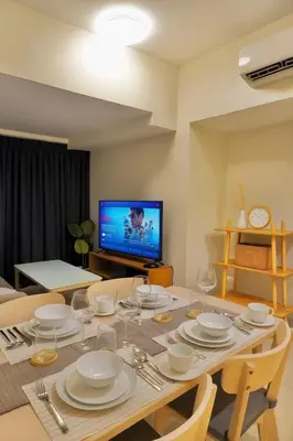 a dining room with a table and a television at Bright Corner 2BR Suite with Bathtub Uptown BGC in Manila