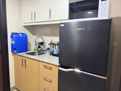 a kitchen with a black refrigerator and a sink at Bright Corner 2BR Suite with Bathtub Uptown BGC in Manila