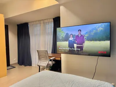a room with a tv on a wall with a desk at Bright Corner 2BR Suite with Bathtub Uptown BGC in Manila