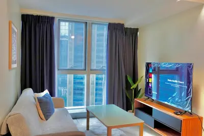 a living room with a tv and a large window at Bright Corner 2BR Suite with Bathtub Uptown BGC in Manila