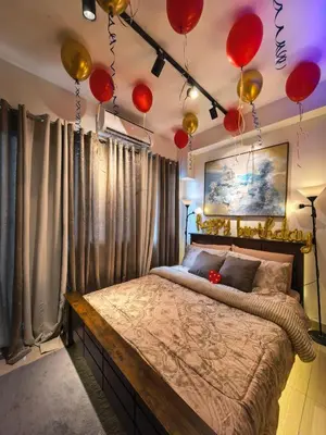 a bedroom with a large bed with red balloons on the ceiling at Irene's luscious place in Manila