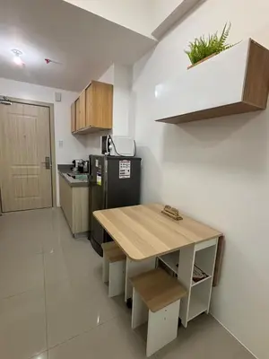a kitchen with a wooden table and a refrigerator at Modern Minimalist City Views in Prime Location in Manila