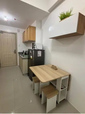a kitchen with a wooden table and a refrigerator at Modern Minimalist City Views in Prime Location in Manila
