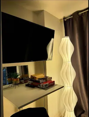 a living room with a tv and a shelf with a television at Nook Out at Azure Urban Residences in Manila