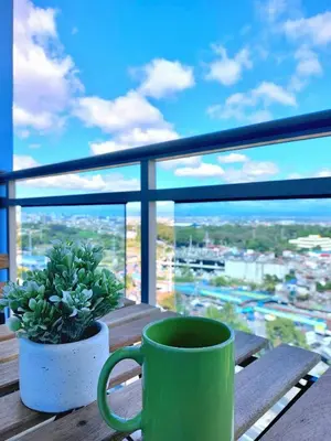 a green coffee cup sitting on a table with a plant at Nook Out at Azure Urban Residences in Manila