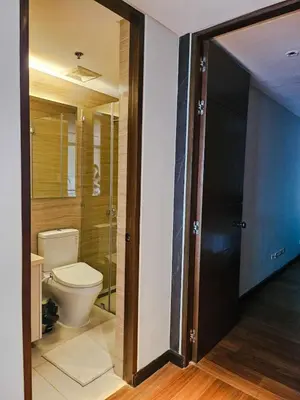 a bathroom with a toilet and a glass door at 2 Bedroom Urban Oasis Poblacion in Manila