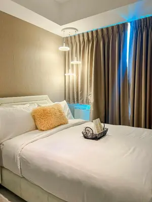 a bedroom with a large white bed and a window at La Luana Mnl in Manila