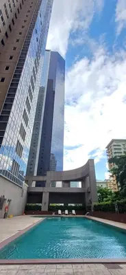 a swimming pool in front of a building with tall buildings at Cozy Haven in Manila