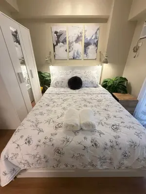 a bedroom with a bed with two towels on it at Aesthetic Cozy Modern Condo Apartment in Manila