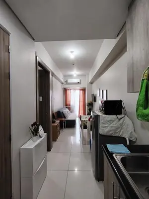 a kitchen with a sink and a living room at Condotel-Coast Residences in Manila