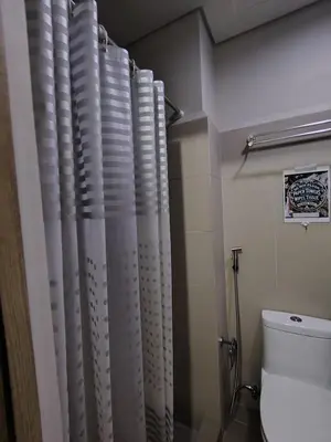 a bathroom with a toilet and a shower curtain at Condotel-Coast Residences in Manila