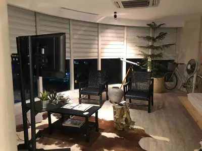 a living room with chairs and a tv and a table at 55-SQM The Urban Cabin in Poblacion Makati in Manila