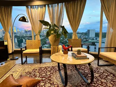 a living room with a table and a large window at 55-SQM Urban Cabin in Poblacion Makati in Manila