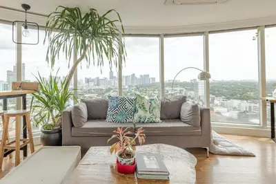 a living room with a couch and large windows at 55-SQM Stunning View Wood House Poblacion Makati in Manila