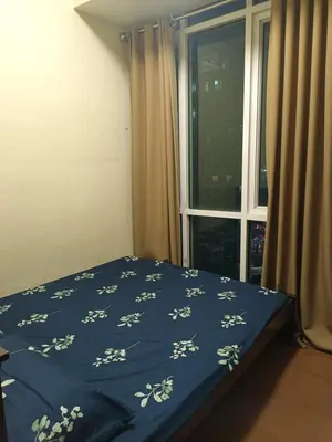 a bed with a blue blanket with white flowers on it at Affordable Condo Staycation at San Lorenzo place condominium in Manila