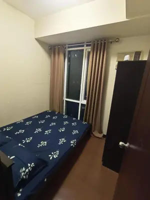 a bedroom with a bed with a blue comforter and a window at Affordable Condo Staycation at San Lorenzo place condominium in Manila
