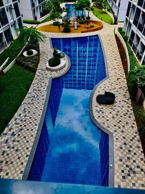 a swimming pool in a resort with blue water at Hotel De Rama Unit 5115 near MOA and NAIA in Manila