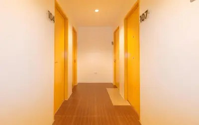 a hallway with orange and white walls and wooden doors at RedDoorz at Zenova Hotel in Manila