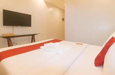 a bedroom with a bed with a tv on the wall at RedDoorz at Zenova Hotel in Manila