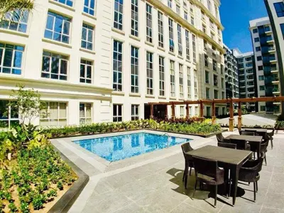 a large building with a pool and tables and chairs at Luxurious & Elegant Vibe in Newport City Pasay in Manila