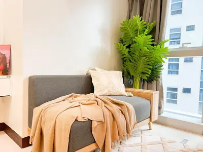 a couch with a blanket on it next to a window at Stylish 1BR Prime BGC Uptown near Hyatt #upt119c in Manila