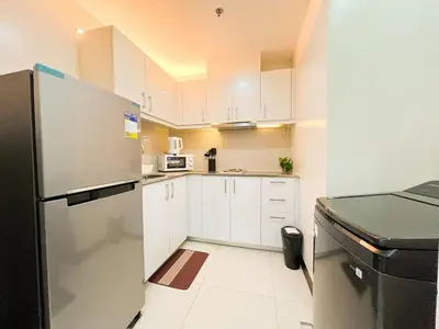 a kitchen with white cabinets and a black refrigerator at Stylish 1BR Prime BGC Uptown near Hyatt #upt119c in Manila