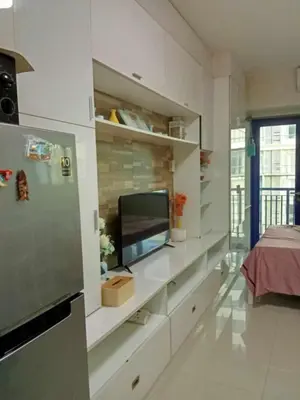 a living room with white cabinets and a television at V&G Era Staycation in Manila