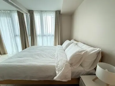 a bedroom with a bed with white sheets and a window at Uptown Suites in Manila