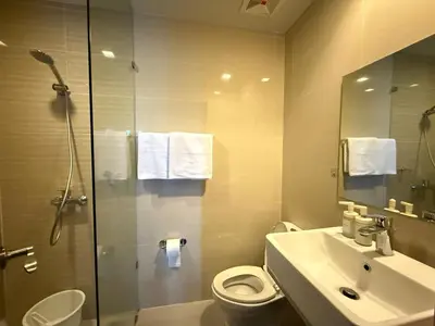 a bathroom with a toilet and a sink and a shower at Uptown Suites in Manila