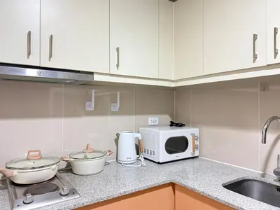 a kitchen counter with a microwave and a sink at Uptown Suites in Manila