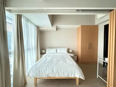 a bedroom with a bed and a large window at Uptown Suites in Manila