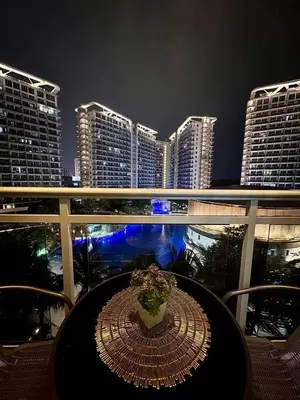 a table on a balcony with a view of a city at night at Dream Escapade in Manila