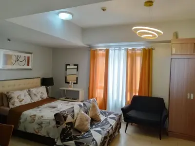 a bedroom with a bed and a chair at Jentry condotel in Manila