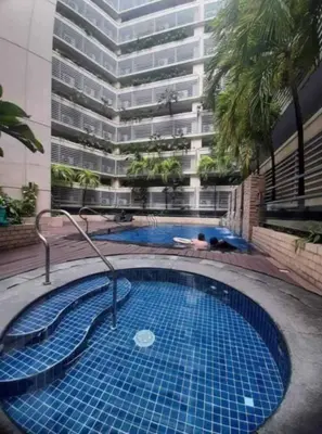 a swimming pool in front of a tall building at Jentry condotel in Manila