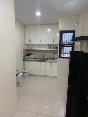a kitchen with white cabinets and a white tile floor at 4 stores with rooftop in Manila