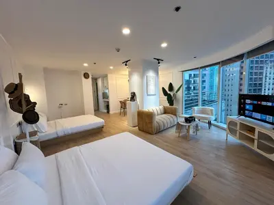 a large white bedroom with a view of a city at Chic Urban Stay with Balcony & Bathtub in Poblacion in Manila