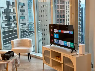 a living room with a television and a chair and a large window at Chic Urban Stay with Balcony & Bathtub in Poblacion in Manila