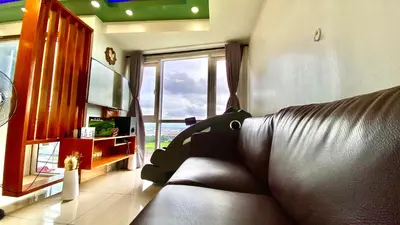 a living room with a leather couch and a large window at Stunning view staycation near MOA PICC WORLD TRADE CENTER AIRPORT LUNETA PARK MANILA OCEAN PARK QURINO GRANDSTAND in Manila