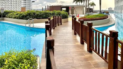 a swimming pool with a walkway next to a building at Stunning view staycation near MOA PICC WORLD TRADE CENTER AIRPORT LUNETA PARK MANILA OCEAN PARK QURINO GRANDSTAND in Manila