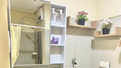a bathroom with a shower with a mirror and shelves at Cozy accommodation near MOA AIRPORT WORLD TRADE AND PICC in Manila