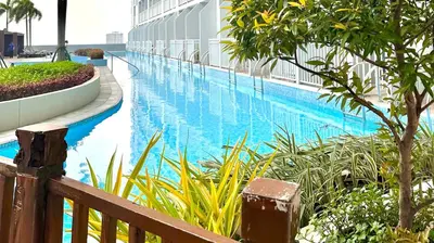 a swimming pool next to a building with a resort at Cozy accommodation near MOA AIRPORT WORLD TRADE AND PICC in Manila