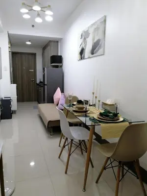 a living room with a dining table and a couch at Vistaro Stays at Fame Residences in Manila